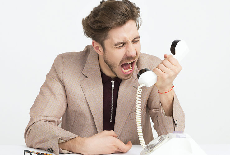 Un homme qui crie dans l'écouteur d'un téléphone fixe