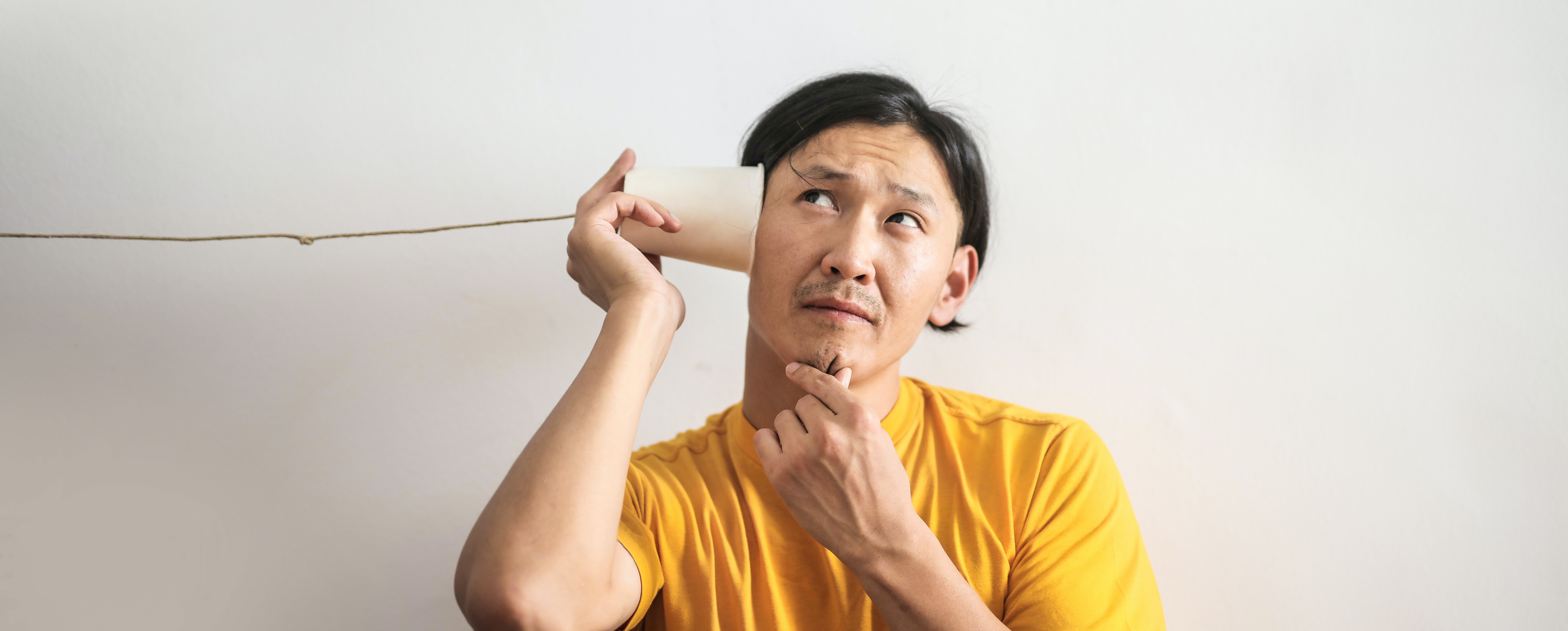 Un homme qui porte un gobelet à son oreille